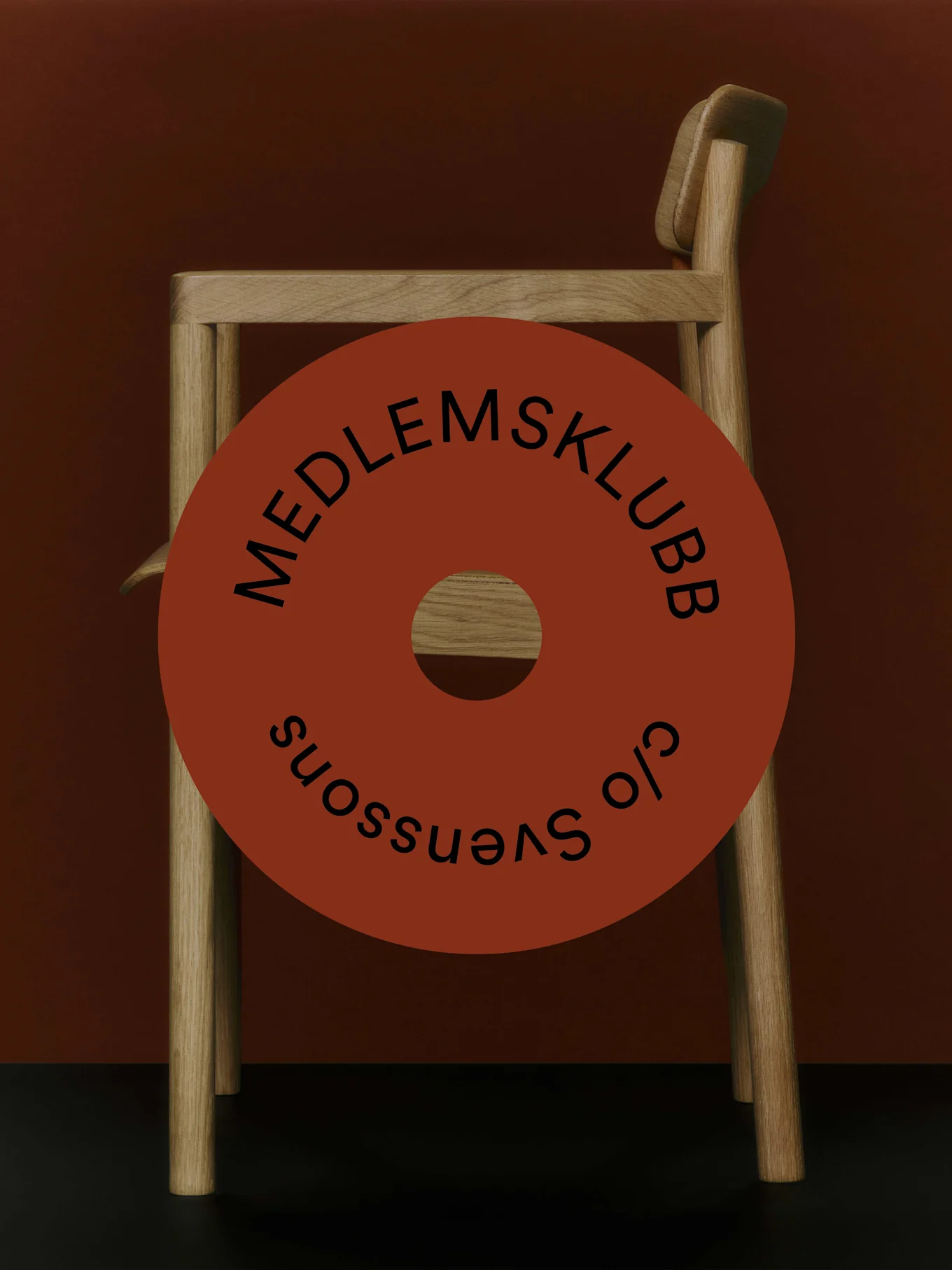 Trästol med en röd cirkulär grafik som säger 'MEDLEMSKLUBB c/o Svenssons'.