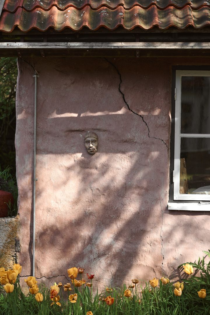 Överallt på Capellagården möts man av vackra byggnader, blommor och grönska, men även roliga detaljer. Här rosa husfasad med en skulptur på väggen.