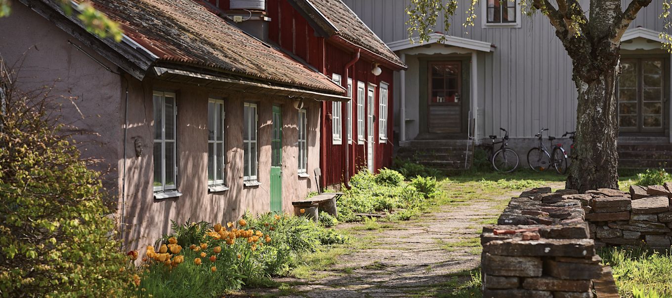 Bild som föreställer delar av Capellagården med verkstäder i olika byggnader, här rosa kalkstenshus bredvid falurött trähus.