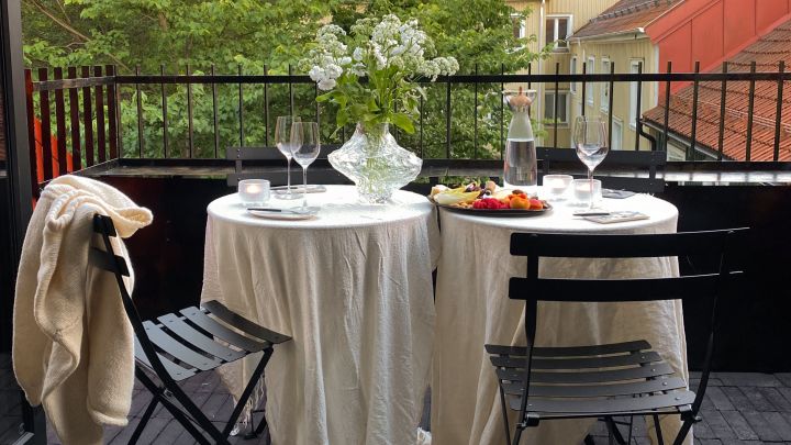 Uppdukat med Bistro caféstolar och bord från Fermob på Elin Lannsjös balkong. Här med vita linnedukar, ljuslyktor, vas me blommor, vinglas och fat med frukt och nötter.