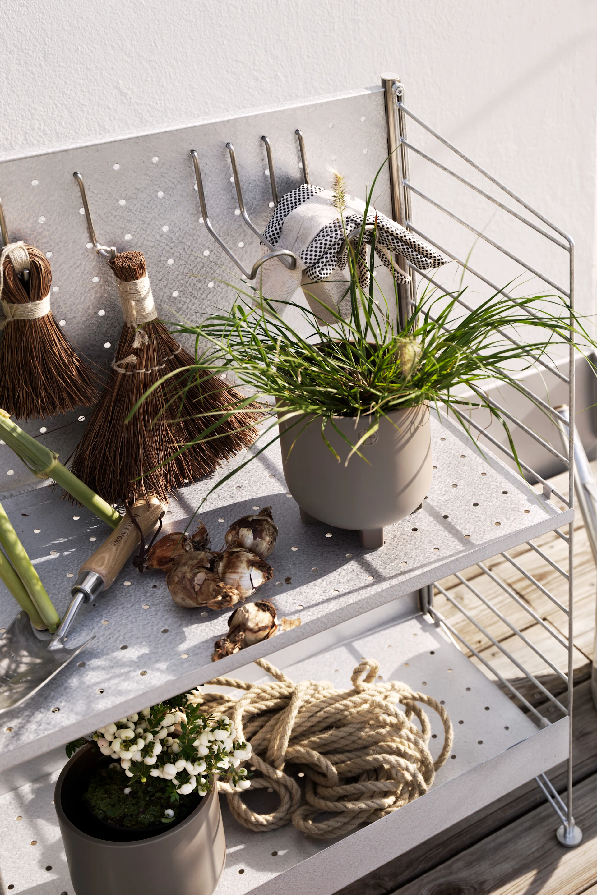 Stringhyllor för utomhusbruk är ett fint exempel på utomhusinredning som ramar in uteplatsen och samtidigt ger plats att förvara krukor, lyktor och fina trädgårdsredskap.