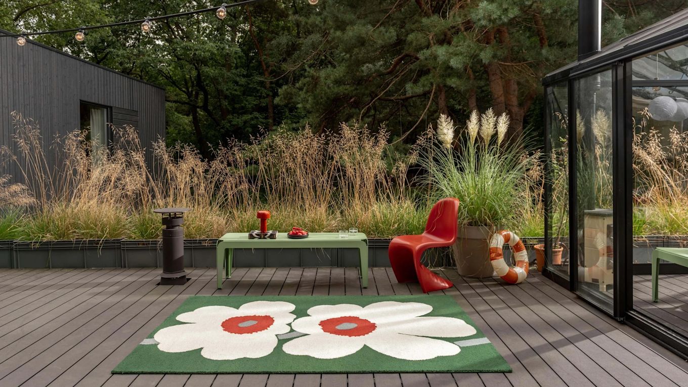 Bild som visar Unikko matta från Marimekko på uteplats, här i grönt med stora vita Unikko-blommor.