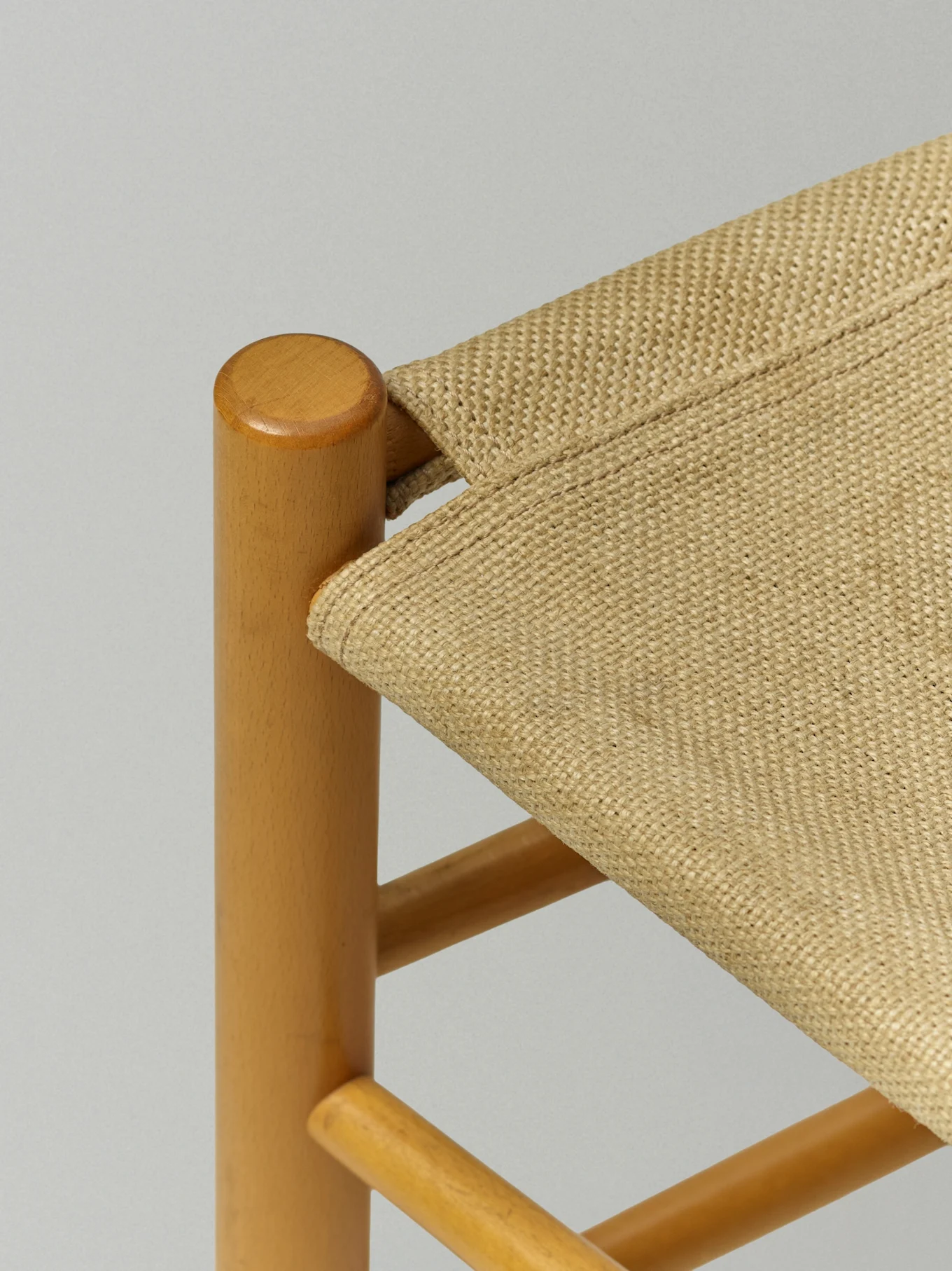 Närbild av en stol med ljusbrun träram och en flätad beige sits.