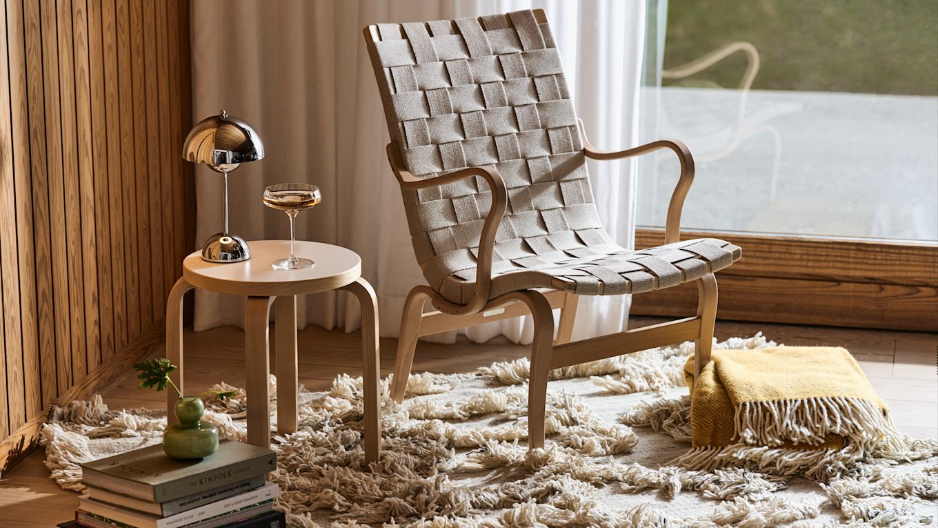 Eva fåtölj från Bruno Mathsson, här tillsammans med Rio ullmatta från Classic Collection, E60 pall från Artek och Flowerpot portabel lampa i krom, alla möbler och detaljer som förstärker känslan av tidlös inredning.